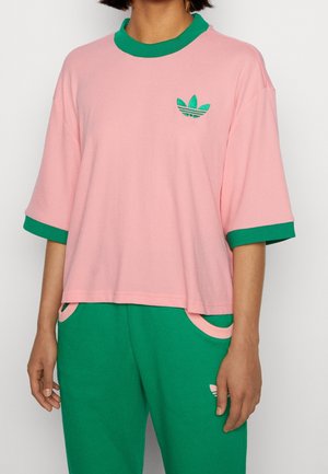 Rosa T-Shirt mit kurzen Ärmeln, grünem Kragen und grünen Akzenten, mit einem kleinen grünen Logo auf der Brust. Weicher, leichter Stoff.