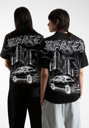 Black t-shirt featuring a graphic design of skyscrapers and a car, with white and gray accents. The front displays a logo detail at the hem.