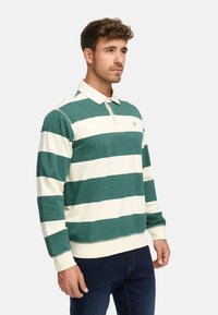 Camisa polo de manga larga a rayas verdes y blancas con un cuello clásico. Presenta un pequeño logo en el pecho y puños acanalados.