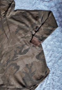 Brązowa bluza z kapturem w kamuflażowy wzór, z dużym kapturem i ściągaczami na rękawach. Miękki materiał i luźny krój z symetrycznym wzorem.