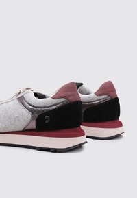 Des chaussures de sport présentant un mélange de feutre gris, de bordeaux, de daim noir et d'accents métalliques. Semelle épaisse avec un design stratifié. Lacets à l'avant.