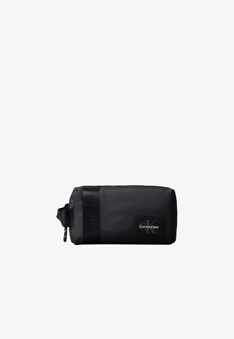 Μαύρο ορθογώνιο νεσεσέρ με λογότυπο Calvin Klein και λεπτομέρεια ιμάντα με το εμπορικό σήμα σε λευκό φόντο.