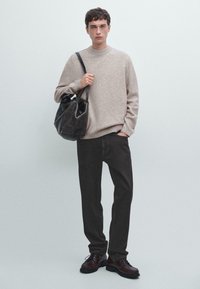 Beige wool sweater, dark jeans, brown lace-up shoes, and a black leather bag. Simple design, textured knit, and casual fit.
