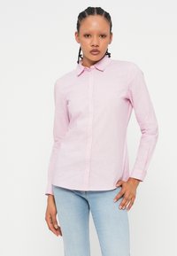Camisa de botão às riscas rosa e branca com colarinho, mangas compridas e um hem ligeiramente curvado, feita de um tecido suave.