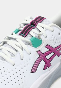 Białe buty sportowe z siateczki i materiałów syntetycznych, z różowymi i turkusowymi akcentami, wyraźnymi perforacjami oraz kontrastującymi sznurówkami.