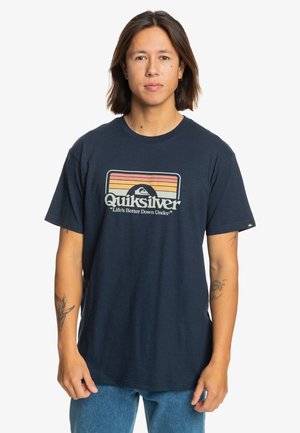 Camiseta de algodón azul marino con un logo de Quiksilver en colores retro y el eslogan "La vida es mejor en Down Under" debajo. Mangas cortas.
