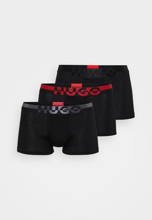 Három pár fekete boxer alsónemű, kontrasztos elasztikus derékpántokkal, piros, szürke és fekete színben, a "HUGO" márkanevével vastag betűkkel kiemelve.