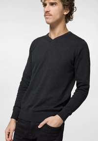 Czarny sweter dzianinowy z dekoltem w serek, z prążkowanymi mankietami i dołem, z małym logo na klatce piersiowej. Slim-fit, gładka tekstura.
