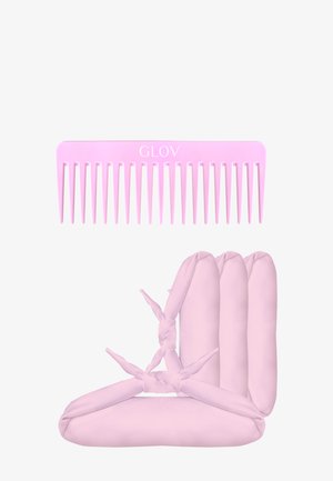 Pettine di plastica rosa con denti larghi, contrassegnato con "GLOV," posizionato sopra tre rulli di tessuto rosa legati alle estremità, disposti a forma triangolare.