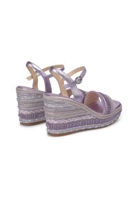 Sandali wedge espadrille viola con suola in juta intrecciata, dettagli metallici e cinturini alla caviglia regolabili. Dettagli in tessuto testurizzato su tutta la scarpa.