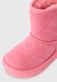 Ružové semišové ankle boot s mäkkým interiérom, okrúhlou špičkou a textúrovanou podrážkou. Obsahuje dekoratívny detail prešívania pozdĺž strany.