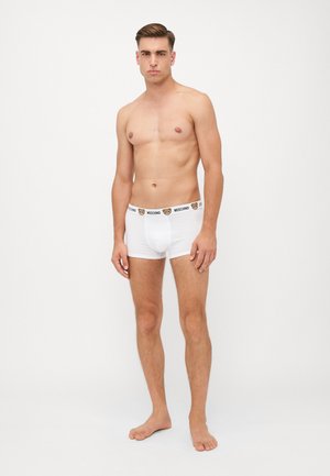 Biele boxerky s čiernym pásom s logom Moschino, priliehavý strih, mäkký materiál, bez viditeľných vzorov alebo akcentov.