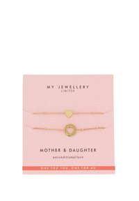 El conjunto de pulseras madre-hija en tono dorado presenta un charm de corazón y un charm de círculo en delgadas cadenas trenzadas, presentado en una tarjeta rosa con texto.
