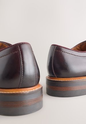 Dunkelburgunderrote Lederschuhe mit glatter Oberfläche, kontrastierenden Holzsohlen und feiner Naht entlang der Kanten. Abgerundetes Absatzdesign.