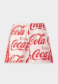 Μπεζ σορτς με κόκκινο λογότυπο Coca-Cola και επαναλαμβανόμενο κείμενο "Enjoy", με ελαστική μέση και κόκκινες πλαϊνές ρίγες.