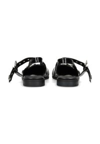 Sandalias de cuero negro con espalda abierta, correa en el tobillo y detalles metálicos plateados. Suela de goma duradera, diseño minimalista y textura suave.