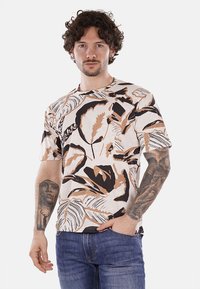 Camiseta de manga corta en beige con un atrevido patrón floral en marrón oscuro y naranja; tejido suave; cuello redondo; corte relajado; diseño casual.