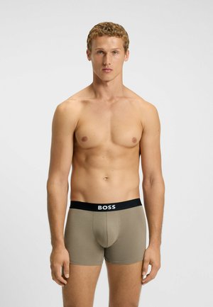 Men's boxer briefs in a light brown color, featuring a black elastic waistband with "BOSS" logo. Smooth fabric and fitted design.