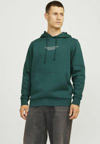 Dunkelgrüner Hoodie aus weichem Stoff, mit einer Fronttasche, verstellbarem Kordelzug in der Kapuze und weißem Logo-Text auf der Brust.