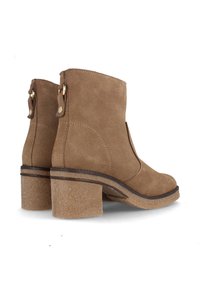 Botas de tobillo de ante marrón con un diseño curvado, tacón bloques y acentos en tono dorado en la parte trasera para facilitar su uso.