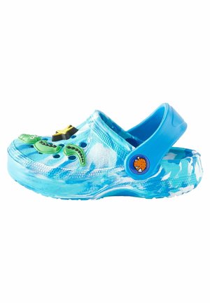Zueco azul para niños con adornos con temática oceánica, incluyendo una estrella, algas marinas y un botón en forma de pez en la correa ajustable del talón.