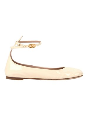 Beige patent leather flat shoe with rounded toe and thin ankle strap featuring a small gold buckle detail.