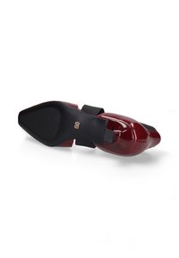 Glanzende bordeaux patent leren schoen met een puntige neus. Zwarte elastische band op de middenvoet. Platte, gestructureerde zwarte rubberen zool.
