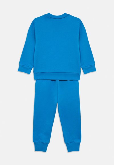 Sininen puuvillainen collegepaita ja collegehousut. Pitkät hihat, joissa resorit hihansuissa, ja pyöreä pääntie. Pehmeä pinta, yksivärinen.