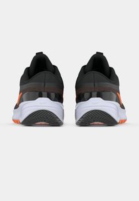 Černé sportovní boty s oranžovými akcenty, s hladkým syntetickým svrškem a texturovanou podešví, navržené pro pohodlí a podporu.