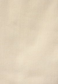 Tela beige con una textura suave y un patrón de tejido diagonal, que presenta variaciones sutiles en el tono, adecuada para diversas aplicaciones textiles.