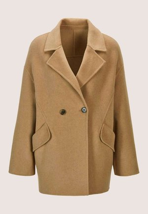 Kamelhaarfarbener Wollmix, übergroßer Mantel mit breiten Revers, doppelt geknöpftem Verschluss und aufgesetzten Taschen auf einem einfarbigen Hintergrund.