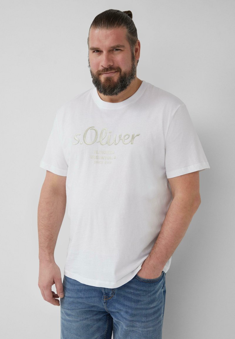 Weißes Baumwoll-T-Shirt mit kurzen Ärmeln, das den gestickten Markennamen "s.Oliver" in Hellgrau zeigt. Kombiniert mit blauen Jeans.