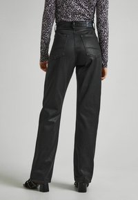 Jeans de mezclilla negra de tiro alto con pierna recta, que presentan dos bolsillos traseros y detalles de costura sutiles. Textura suave.