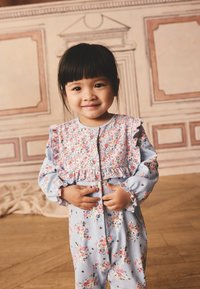 Floral-patterned, light blue onesie with ruffled accents at the shoulders and cuffs, featuring a button closure and soft fabric texture.