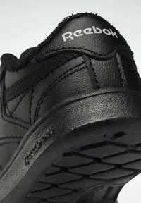 Černá kožená bota s texturovaným povrchem, vybavená gumovou podrážkou a viditelným logem Reebok na patě.