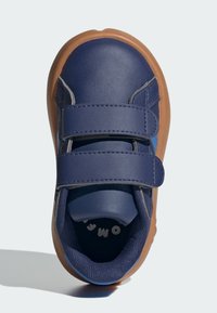 Chaussure pour enfant bleu marine avec deux bandes Velcro, dessus en cuir synthétique et semelle en caoutchouc marron. Intérieur texturé avec détail de logo.