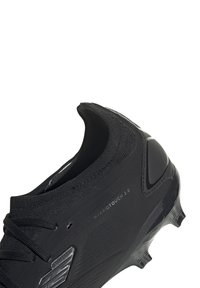 Scarpe sportive nere con un design elegante, tomaia texturizzata, colletto elastico a forma di calza e dettagli del tallone sagomati. Suola in gomma nera con tacchetti.