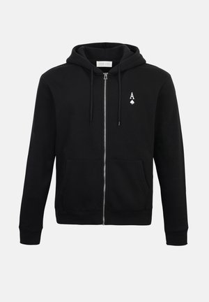 Svart hettejakke med glidelås laget av mykt stoff, med en lomme foran, snor i hetten og en liten hvit spar-emblem på venstre bryst.