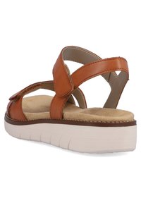 Sandale en cuir marron avec des sangles ajustables, semelle rembourrée et une semelle plateforme blanche et texturée. Vue latérale mettant en avant le design et les matériaux.