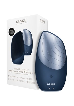 Mørkeblå GESKE Sonic termo-facial børste med strukturerede silikonebørster og buet design, vist ved siden af hvid produktemballage.