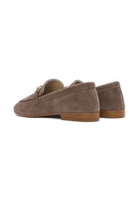 Mocassini in suede marrone con suola in gomma piatta, caratterizzati da un design slip-on e un piccolo dettaglio decorativo a strappo sulla parte superiore.