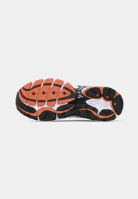 Black and white running shoe sole featuring prominent orange rubber treads, textured patterns, and ventilation details for enhanced grip and flexibility.