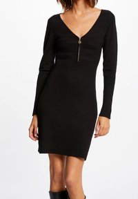 Černé těsné šaty s dlouhými rukávy, hlubokým V-výstřihem, předním zipem, vroubkovanou strukturou a přiléhavým střihem.