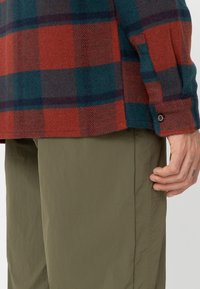 Rød og blå ternet flannel skjorte med en blød tekstur og knappet manchet, parret med olivengrønne letvægtsbukser.