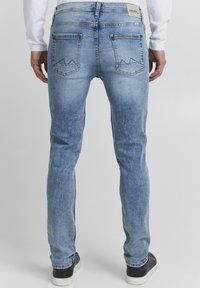 Ljust blå denimjeans med slim fit, som har två bakfickor med dekorativ sömnad och en lätt blekning. Bärs med mörka sneakers.