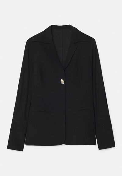 Blazer noir avec un col à revers, fermeture à un bouton doré, deux poches avant et des manches longues avec une texture lisse.