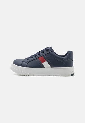 Sneaker blu navy con tomaia in pelle, suola in gomma bianca e strisce rosse e bianche a contrasto lungo il lato. Design con lacci, forma bassa.