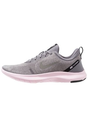 Boční pohled na šedou běžeckou obuv Nike s světle růžovou podrážkou, přední šněrování a černý tahák na patě.