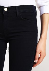 Mörkblå jeans i stretchdenim, med klassisk passform, subtil sömnad och en framficka med metallknappförslutning.