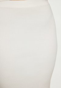 Materialul textil cu dungi, de culoare crem, pentru o fustă mulată. Textură netedă cu o ușoară strălucire, având o talie înaltă și o siluetă elegantă.